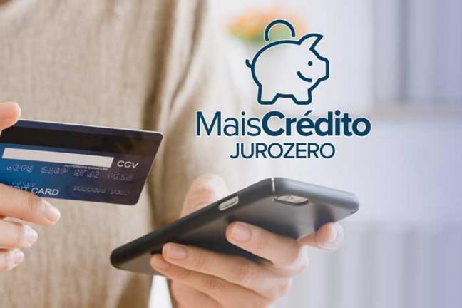 Pessoa segurando um celular e um cartão de crédito, mais texto: Mais crédito juro zero