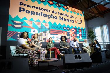 Mesa de abertura com (esq. para dir.): coord. Políticas Públicas de Saúde CPPS)/DAPS/SMS, Gisele Martins Gomes, a dir.-adjunta DAPS, Caroline Ceolin, a secretária-adjunta, Jaqueline César Rocha, a RT das Política de Saúde da População Negra da SES RS, Francyne Silva, o representante da Coord. Nacional de Saúde da População Negra do Ministério da Saúde, Hilário Damásio e a Coord. do CMS, Maria Inês Flores e Coord. CoorSaúde UFRGS, Eloá Rossoni. SMS