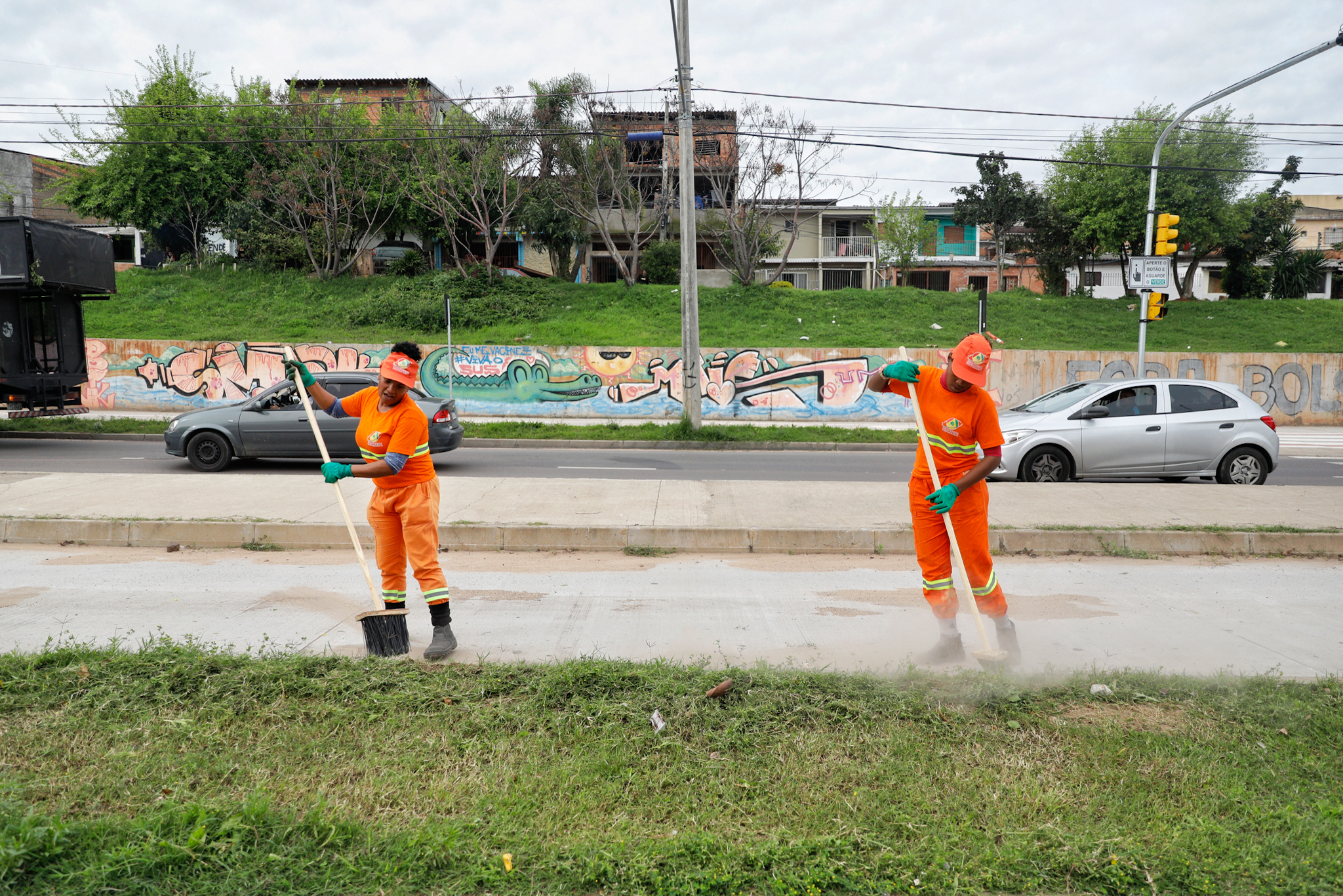 A imagem mostra dois garis realizando limpeza na avenida Cruzeiro do Sul.