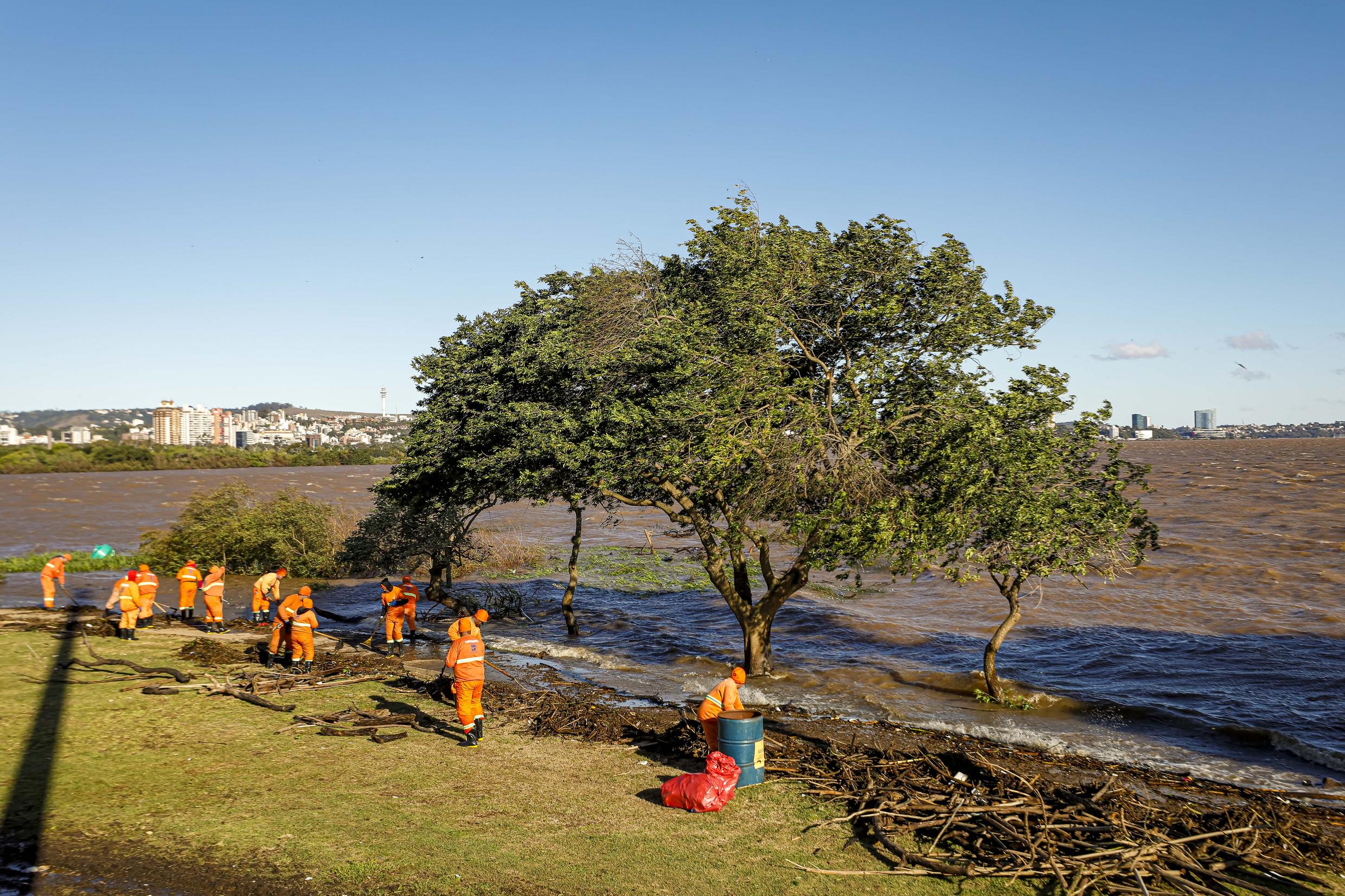 A imagem mostra garis realizando uma ação especial de limpeza na Orla do Guaíba após as chuvas que atingiram a cidade.